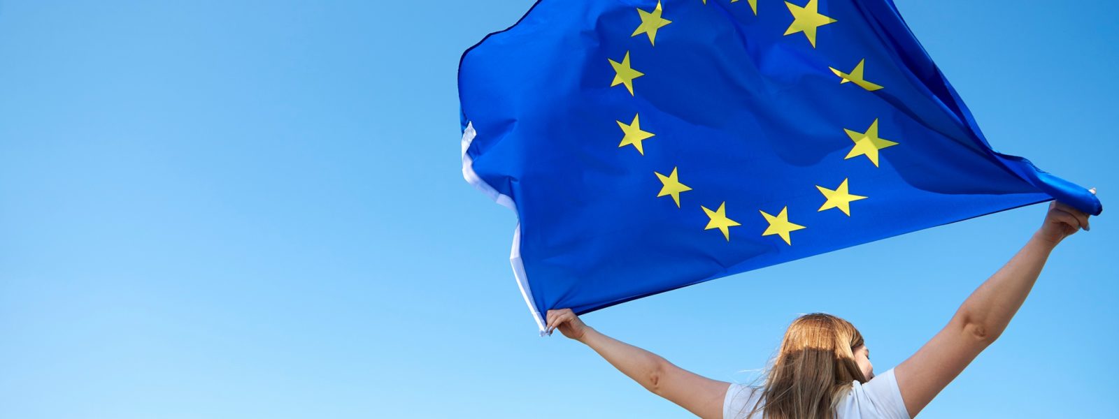 AdobeStock_286829740_Rear view of young woman waving the European Union flag